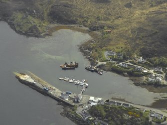 Oblique aerial view centred on the harbour and slipway with the remains of the towerhouse adjacent, taken from the NNW.