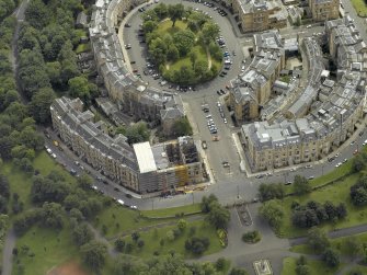 Oblique aerial view centred on the building with fire damaged flats under repair adjacent, taken from the NW.