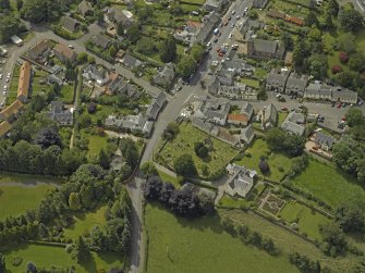 General oblique aerial view of the village centred on the churches, burial-ground and manse, taken from the NE.