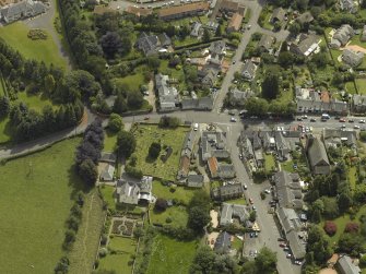 General oblique aerial view of the village centred on the churches, burial-ground and manse, taken from the NW.