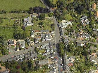 General oblique aerial view of the village centred on the churches, burial-ground and manse, taken from the SW.