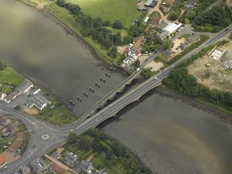 Oblique aerial view centred on the old bridge, rail bridge and new road bridge, taken from the SW.