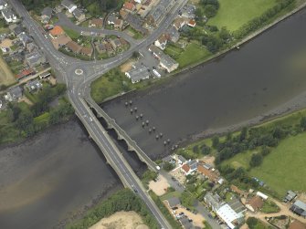 Oblique aerial view centred on the old bridge, rail bridge and new road bridge, taken from the SE.