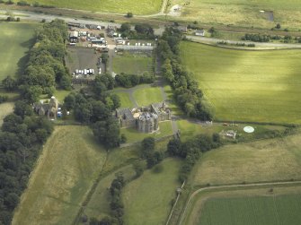 Oblique aerial view centred on the country house with the Collegiate Chapel adjacent, taken from the N.