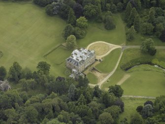 Oblique aerial view centred on the country house with the burial vault adjacent, taken from the NE.