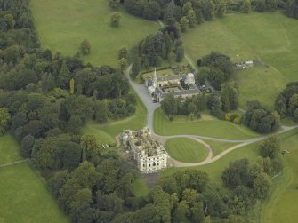 Oblique aerial view centred on the ruins of the house with the stables adjacent, taken from the SSE.