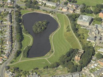 Oblique aerial view centred on the reservoir with the water tower and high school adjacent, taken from the SE.