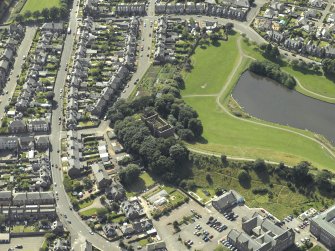 Oblique aerial view centred on the water tower with the high school adjacent, taken from the NE.