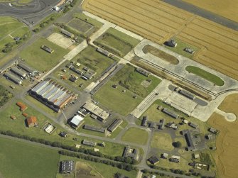 Oblique aerial view centred on the technical area with the control tower adjacent, taken from the NW.