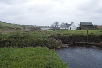 View looking NE towards mill, Millquoy (former miller's cottage) to right and inner face of dam wall and sluice.