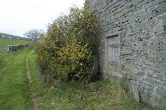 View of replaced possible oatmeal runner stone leaning against SE gable.