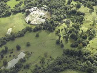 Oblique aerial view centred on the house and walled garden with the earthwork adjacent, taken from the N.