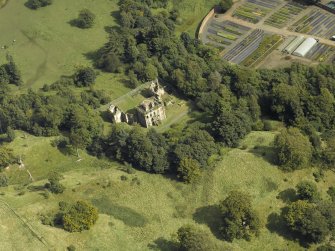 Oblique aerial view centred on the house and walled garden with the earthwork adjacent, taken from the W.