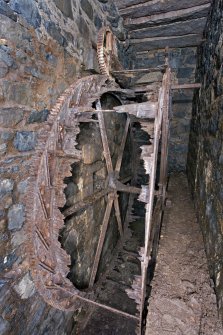 Interior. View of enclosed wheelpit looking towards launder. Note the rim gearing on the waterwheel.