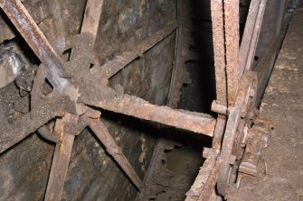 Interior. Detail view of square axle of waterwheel, remians of drum boards visible and bearing block to right of image.