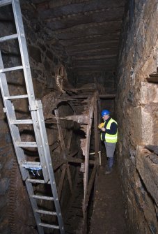 Interior. Waterwheel pit. View of J Borland of RCAHMS undertaking graphic survey.