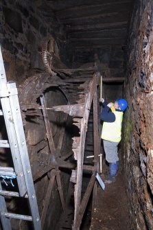 Interior. Waterwheel pit. View of J Borland of RCAHMS undertaking graphic survey.