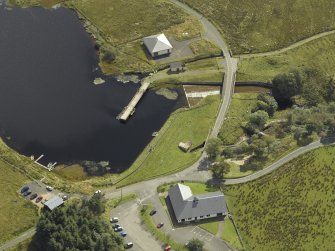 Oblique aerial view centred on the dam and sluice with bridge adjacent, taken from the NW.