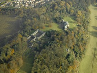 Oblique aerial view centred on the house and stable block, taken from the W.