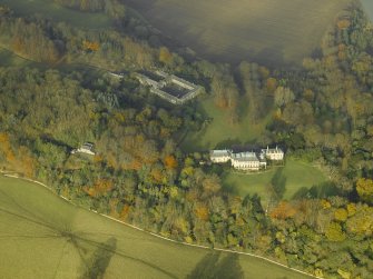 Oblique aerial view centred on the house and stable block, taken from the SSE.