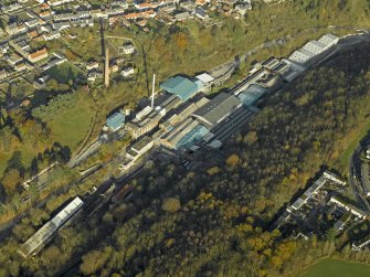 Oblique aerial view centred on the mill and chimney stack, taken from the S.