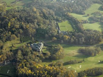 Oblique aerial view centred on the house with the walled garden and stables adjacent, taken from the NW.