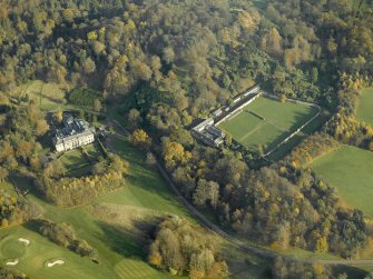 Oblique aerial view centred on the house with the walled garden and stables adjacent, taken from the W.