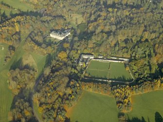 Oblique aerial view centred on the house, walled garden and stables, taken from the SSW.