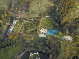 Oblique aerial view centred on the walled garden with the ornamental lake and island adjacent, taken from the W.