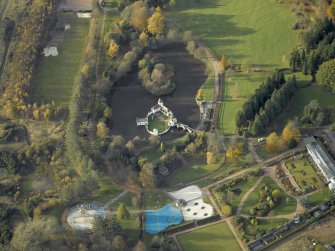 Oblique aerial view centred on the ornamental lake and island with the walled garden adjacent, taken from the ESE.