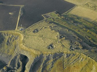Oblique aerial view centred on the remains of the battery with Macduff's cave in the foreground, taken from the ESE.