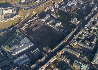 Oblique aerial view centred on the cleared Caltongate development site (former SMT bus garage) with Canongate adjacent, taken from the SW.