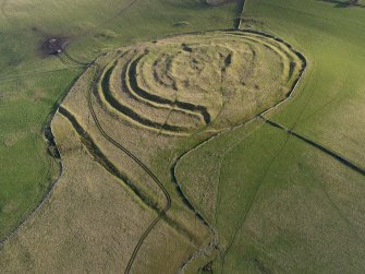 Oblique aerial view centred on the remains of the fort and linear earthwork, taken from the NW.