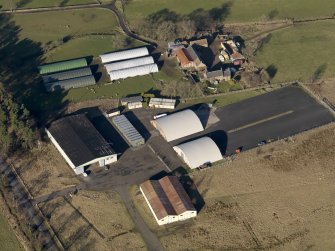 Oblique aerial view centred on the technical area including the aircraft hangars with the farmsteading adjacent, taken from the S.