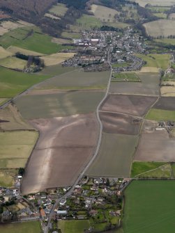 General oblique aerial view centred on the field boundaries with the town and village adjacent, taken from the E.