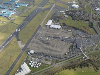 Oblique aerial view centred on the airport terminal buildings with the railway station adjacent, taken from the NW.