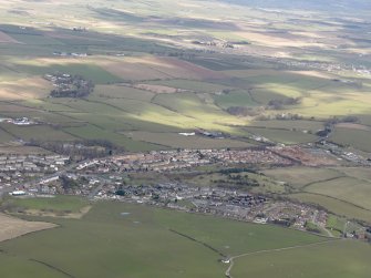 General oblique aerial view centred on the town, with passenger aircraft landing at Prestiwck Airport, taken from the SW.