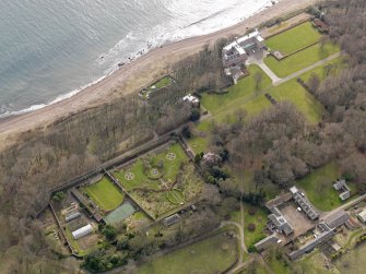 Oblique aerial view centred on the walled garden and orangery with the home farm, houses and tower-house adjacent, taken from the NNW.
