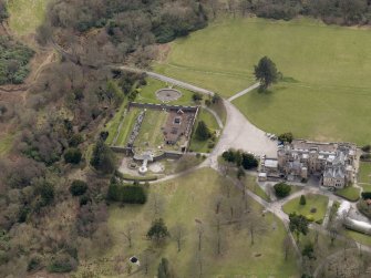 Oblique aerial view centred on the house with the walled garden adjacent, taken from the N.
