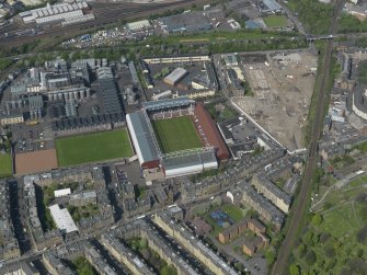 Oblique aerial view centred on the football stadium with the distillery adjacent, taken from the S.