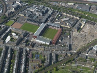 Oblique aerial view centred on the football stadium with the distillery adjacent, taken from the SE.
