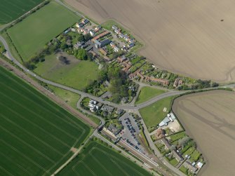 Oblique aerial view centred on the village with the railway station adjacent, taken from the SE.