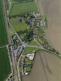 Oblique aerial view centred on the village with the railway station adjacent, taken from the E.