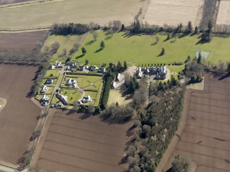 Oblique aerial view centred on the country house, its policies and the modern housing development, taken from the NNW.