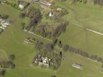 Oblique aerial view centred on the remains of the house with the remains of the stables adjacent, taken from the SSE.