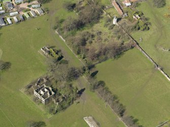 Oblique aerial view centred on the remains of the house with the remains of the stables adjacent, taken from the SE.