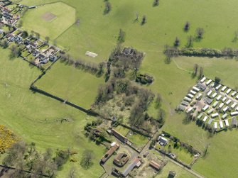 General oblique aerial view centred on the remains of the house with the remains of the stables adjacent, taken from the NW.