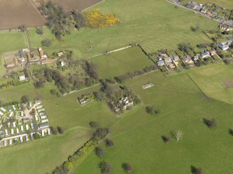 General oblique aerial view centred on the remains of the house with the remains of the stables adjacent, taken from the SW.