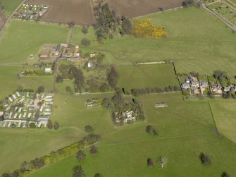 General oblique aerial view centred on the remains of the house with the remains of the stables adjacent, taken from the S.
