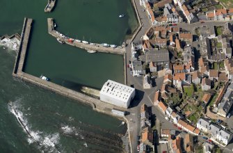 Oblique aerial view centred on the boathouse/boatshed with the harbour adjacent, taken from the E.